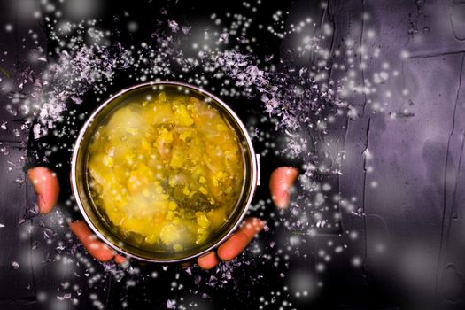 Man in black gloves holding a Cup of soup on a black background.