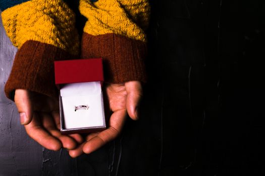 Male hand holds out a ring on a black background