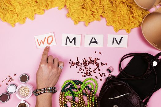 Man in women's jewelry puts the inscription on pink background