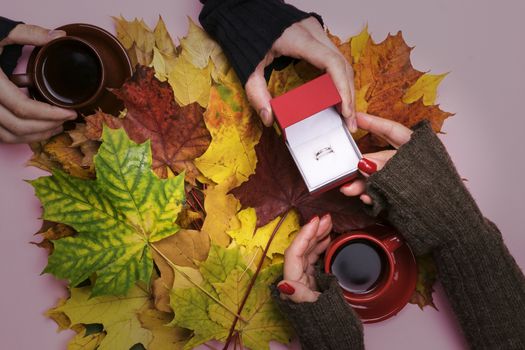 A man gives a ring on the girl on the background of autumn leaves.