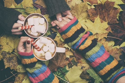 Man and woman drinking coffee in autumn leaves