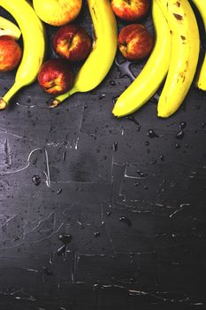 Apples and bananas on a dark background with splashes of water