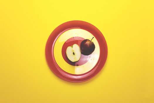 Apple on a red plate on a colored background