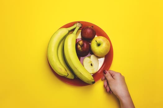 Girl holding a plate of fruit on a color background. The concept of healthy eating, diet.