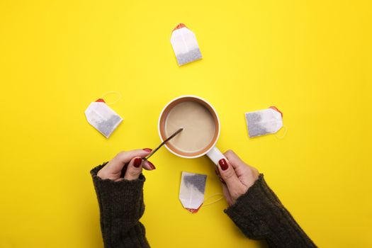 Girl holding a Cup of coffee surrounded by tea bags. The concept of beverages and preferences. Coffee pause, a break.