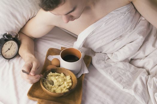 Young man having Breakfast in bed in the morning
