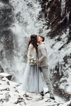 bride and groom on the background of a mountain waterfall