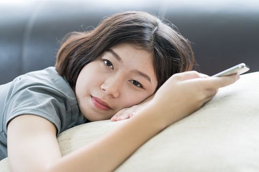 Close up young asian woman short hair listening music from mobile phone on the couch at home