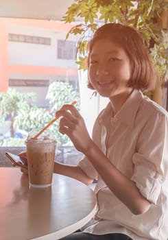 Woman using smartphone in coffee shop and a cup of coffee on the table with soft light vintage filter