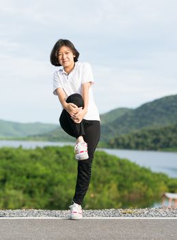 Fitness and lifestyle concept - Young asian woman short hair doing exercising outdoor and warm up preparing for jogging