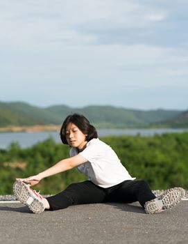 Woman runner doing exercises and warm up preparing for jogging outdoor