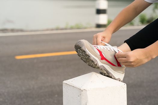 Woman runner tying shoelace his before starting running, Woman doing exercises and warm up before run daily routine workout