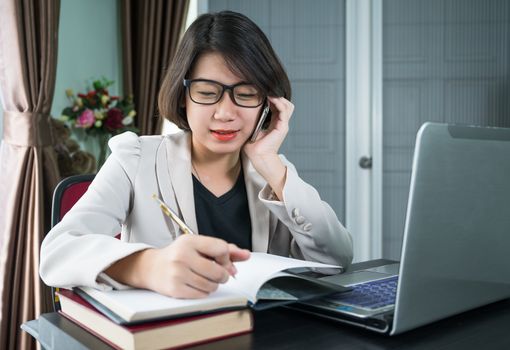 Woman short hair in smart casual wear working on laptop while sitting near window in home office