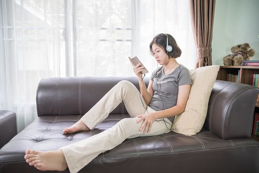 Close up young asian woman short hair listening music from mobile phone on the couch