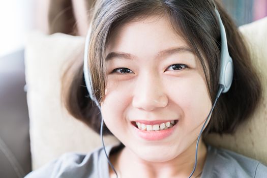 Close up young asian woman short hair listening music from mobile phone on the couch