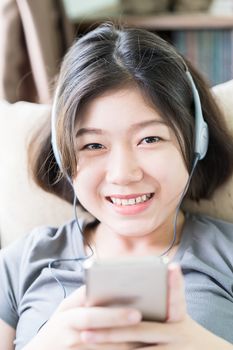 Close up young asian woman short hair listening music from mobile phone on the couch