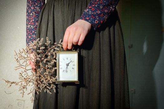 Girl with vintage dress holding clock in hand