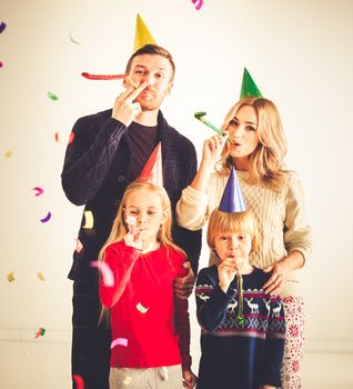 Family blowing party trumpets with confetti celebrating new year