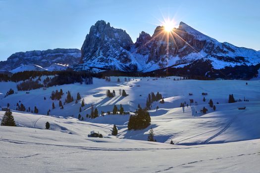 Winter sunrise on Alpe di Siusi with rising sun over Sassolungo and Sassopiatto, Dolomites, Italy