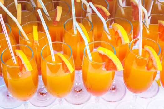 Orange juice cocktail in a flute glasses and slice of fresh orange with draw on white table,closed picture.