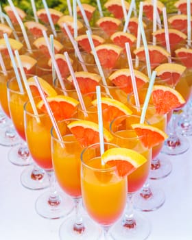 Orange juice cocktail in a flute glasses and slice of fresh orange with draw on white table,closed picture.