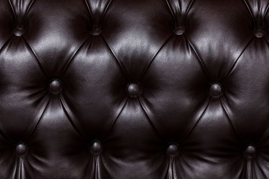 Closeup shot of dark brown leather texture with buttons. Furniture texture