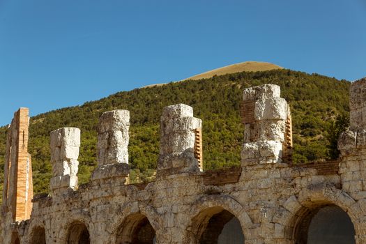 detail of the ancient Roman theater in the background the Ingino mountain full of green fir trees