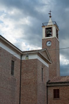 The facade of the ancient church with the bell tower and clock in Marotta, Italy