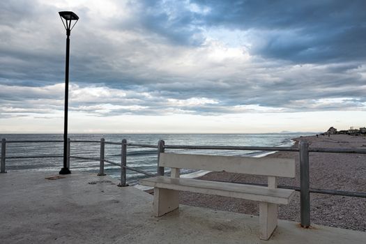 The viewpoint on the beach with bench and street light of Marotta under a cloudy sky, Italy