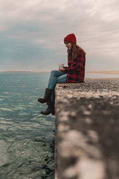 Beautiful woman enjoying her day in the lake with a mug of hot coffee