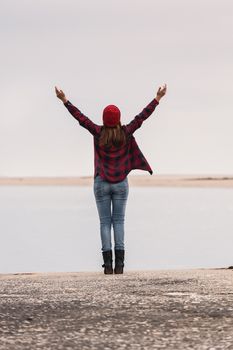 Beautiful woman standing on a pier with arms raised feeling the freedom