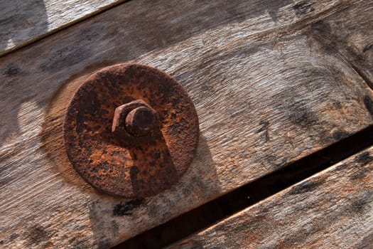 The screw nut is rust on old wood floor.