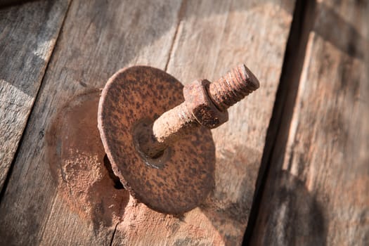 The screw nut is rust on old wood floor.