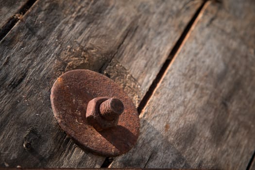 The screw nut is rust on old wood floor.