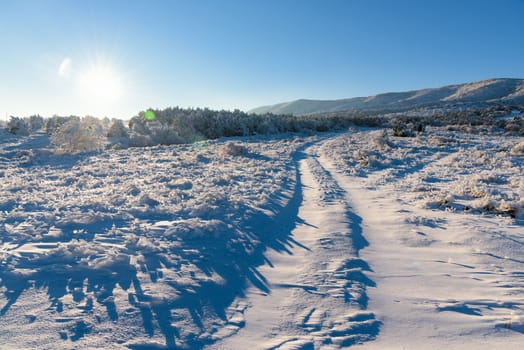 Beautiful winter sunset sunshine with road that leads to frozen mountain