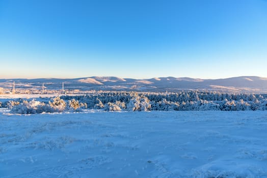 Sunlight falls on frozen mountain, field and pines