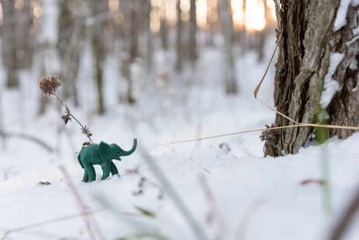 Plasticine green elephant adventure with frozen plant on snow