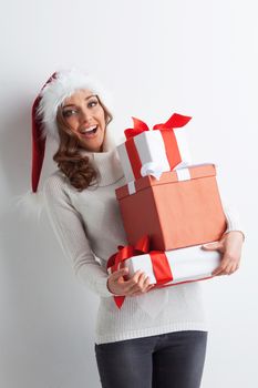 Happy woman in Santa hat with stack of Christmas gifts