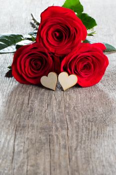 Two roses and wooden hearts on old plank background, Valentines day