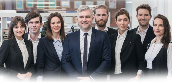 Group of friendly businesspeople with male mature leader in office