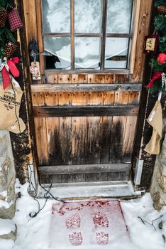 Footsteps in snow in front of a door decorated with Christmas decorations