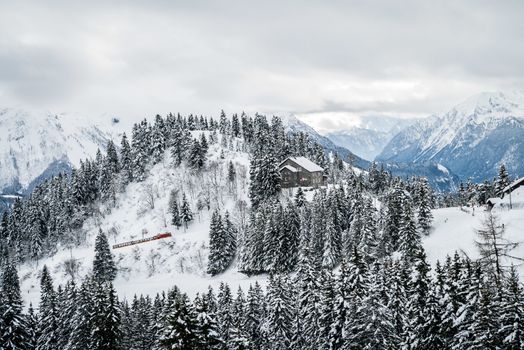 Red train climbing a mountain covered with snow in Villars-sur-ollon in Switzerland