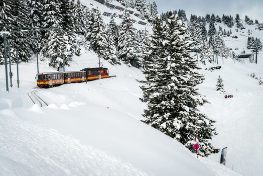 Red train going down the mountain with a lot of snow on the rails