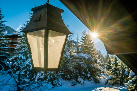 Lantern in the winter with snow in the trees and sun in the background