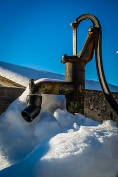 Fountain pump under the snow with a bright blue sky in winter