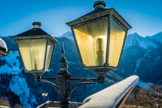 Lantern backlit by the sun with snowy mountains in the background