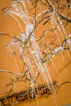 Ice stalactites shining in the sun with an orange wall background