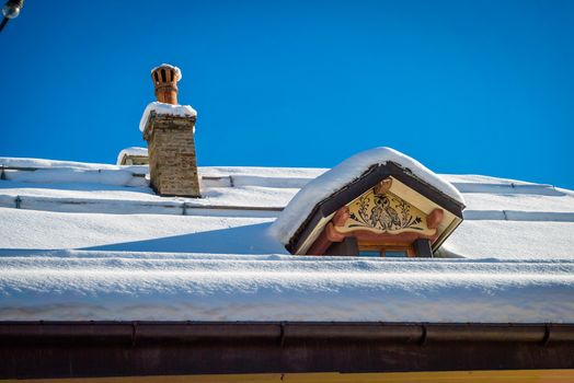 Roof covered with snow with an owl painted on the window in the winter in Switzerland