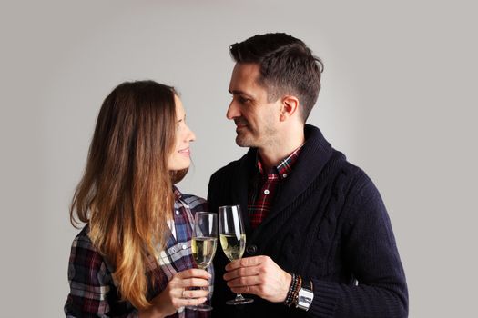 Happy mature couple in casual clothes embracing and clinking glasses of champagne