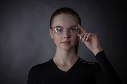 Beautiful woman with transparent futuristic glasses on dark background